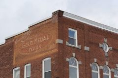 A faded painted logo from the side of an American building.